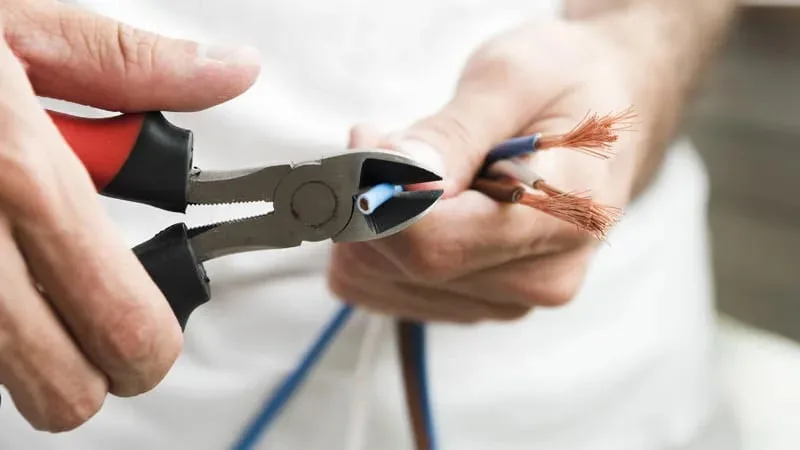 Close-up of hands preparing electrical cable with pliers