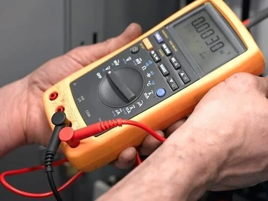 Close-up of a handheld digital multimeter with test leads connected